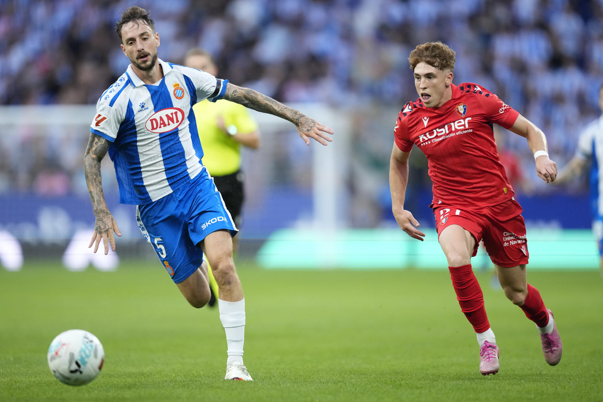 El defensa del Espanyol Fernando Calero (i) se escapa de Víctor Muñoz, de Osasuna, durante el partido de la tercera jornada de LaLiga que RCD Espanyol y Atlético Osasuna jugaron en el RCDE Stadium. EFE/Enric Fontcuberta