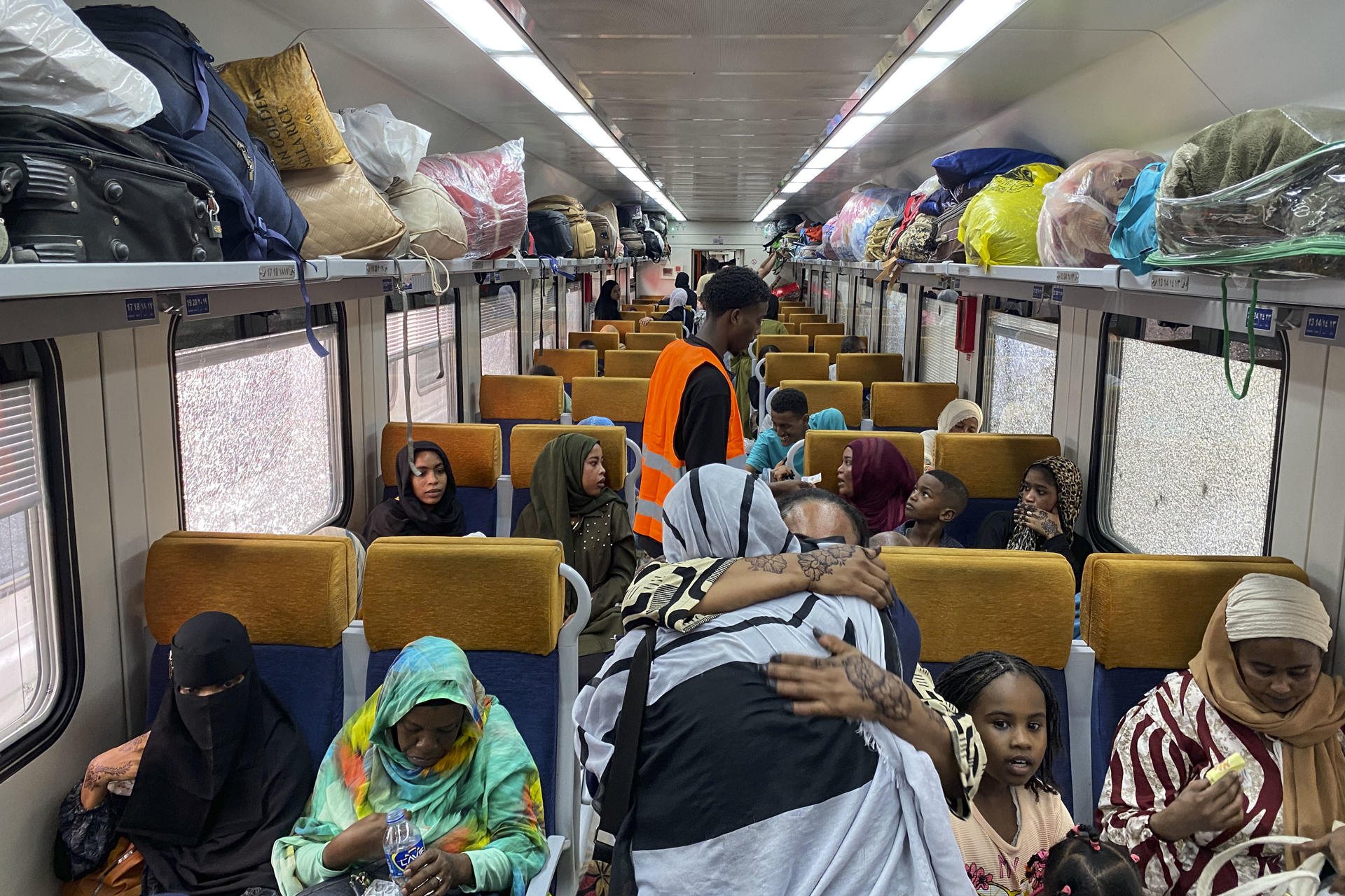 Dos mujeres se despiden con un abrazo en uno de los vagones del tren reservado para que los refugiados sudaneses retornen a su país desde El Cairo. En la céntrica estación de ferrocarril de Ramsés, en El Cairo, el bullicio habitual se mezcla con aires de despedida y esperanza. Alrededor de 940 refugiados sudaneses, cargados con grandes bultos y maletas con pertenencias y recuerdos acumulados durante su exilio, se preparan para abordar el tren que les llevará de regreso a su país. EFE/Rosa Soto