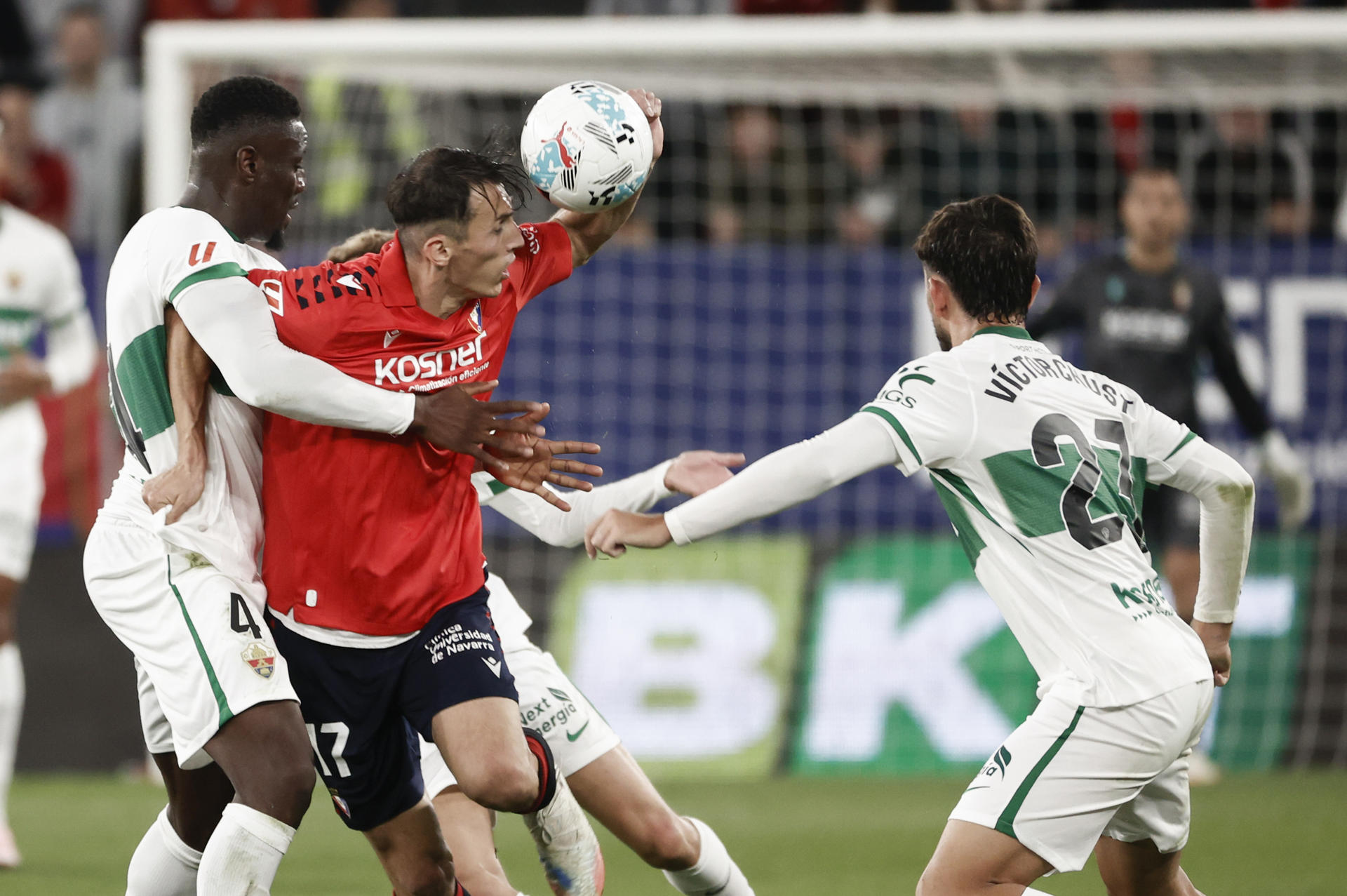 El delantero del Osasuna Ante Budimir (2i) pelea por el balón con los defensas del Elche, Victor Chust (dcha), y Bambo Diaby, durante el partido de la jornada 6 de Liga que disputan este jueves ante el Osasuna en el estadio El Sadar en Pamplona. EFE/Jesús Diges
