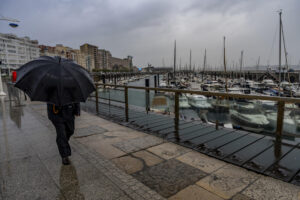 Un hombre se protege de la lluvia por el puerto de Santander. EFE/Román G. Aguilera