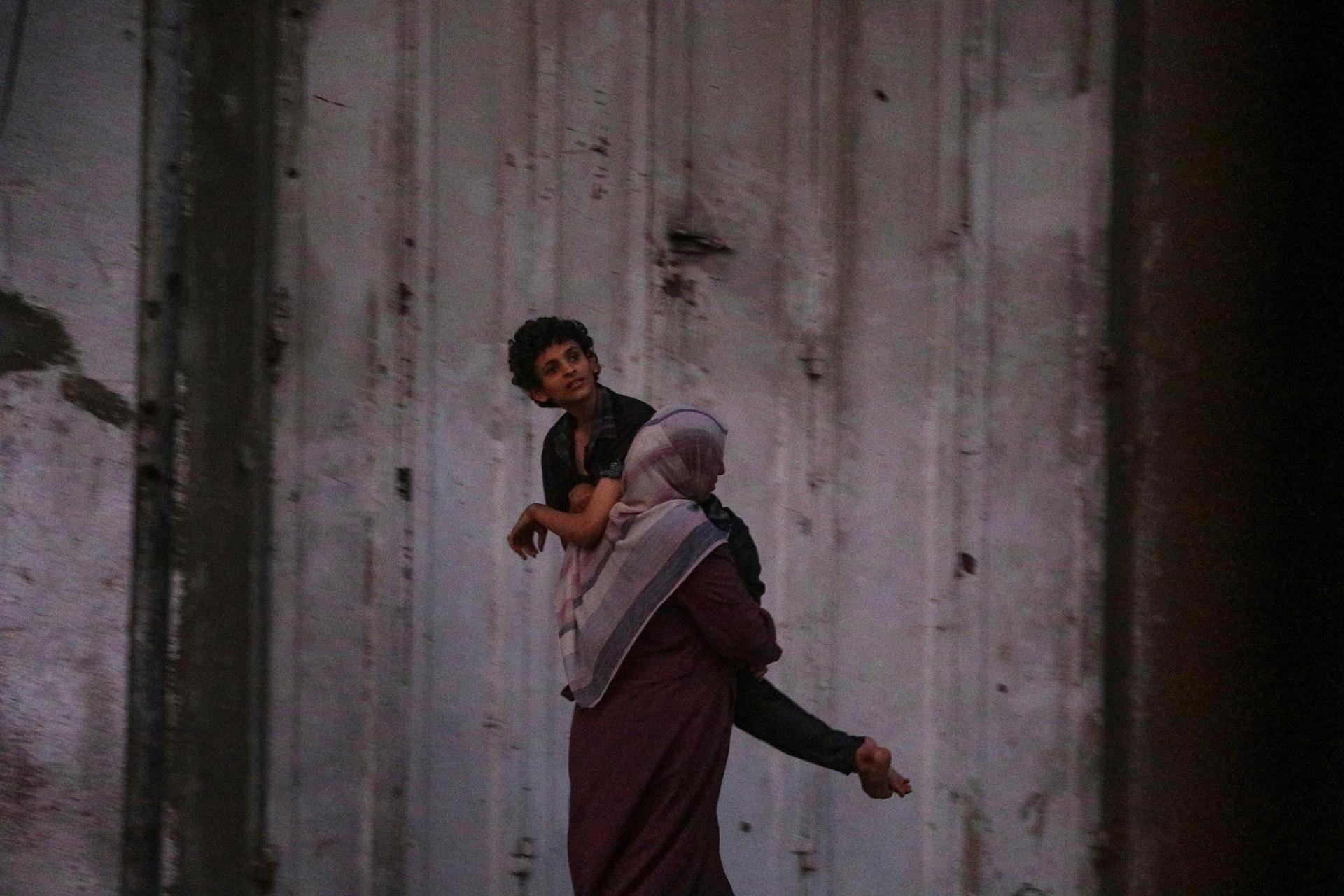 Una madre palestina huye de ciudad de Gaza cargando a su hijo enfermo el 28 de septiembre de 2025. EFE/EPA/MOHAMMED SABER