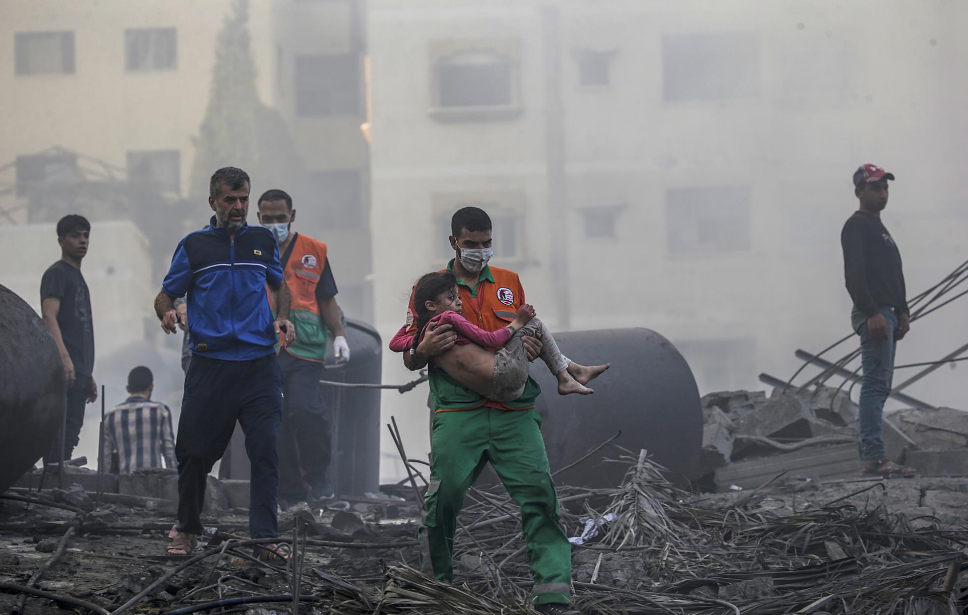 Imagen de archivo de un palestino que carga a una niña herida tras recuperarla de los escombros de una zona destruida tras los ataques aéreos israelíes en la ciudad de Gaza. EFE/EPA/MOHAMMED SABLE