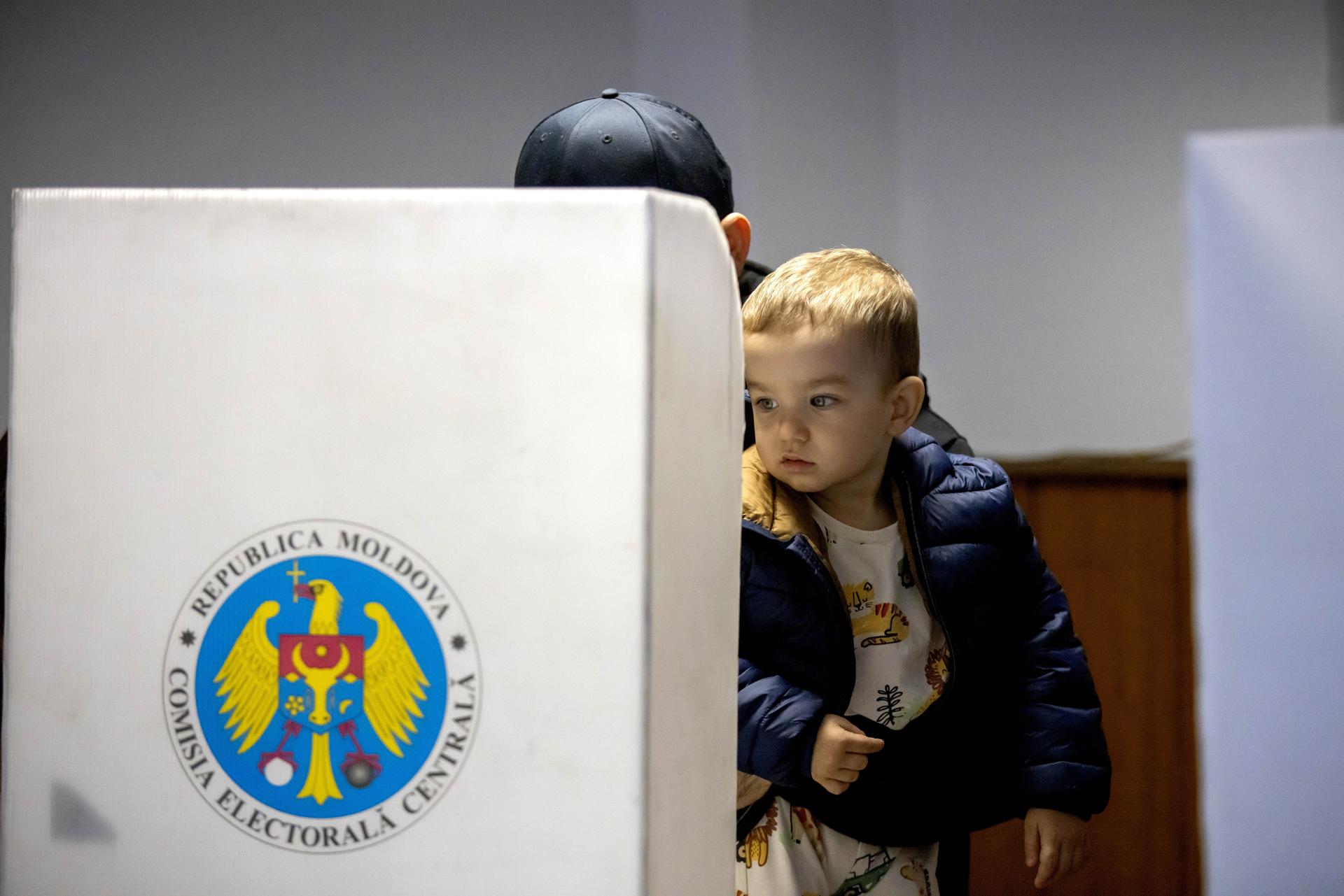 Un votante, acompañado por un niño, participa en Chisinau en las elecciones parlamentarias moldavas EFE/EPA/Dumitru Doru
