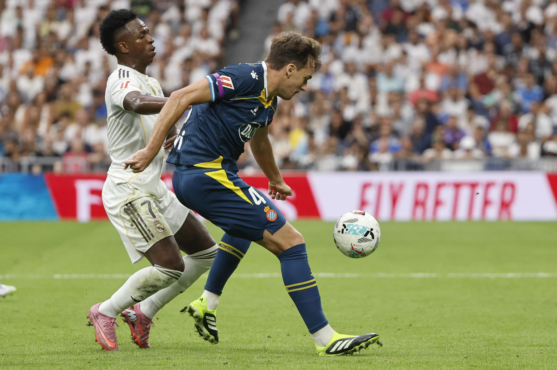 El delantero brasileño del Real Madrid Vinícius Jr pelea un balón ante el centrocampista del Espanyol Urko González (d), durante el partido de la jornada 5 de LaLiga EA Sports que disputaron el Real Madrid y el RCD Espanyol, en el estadio Santiago Bernabéu de la capital española. EFE/ Sergio Pérez