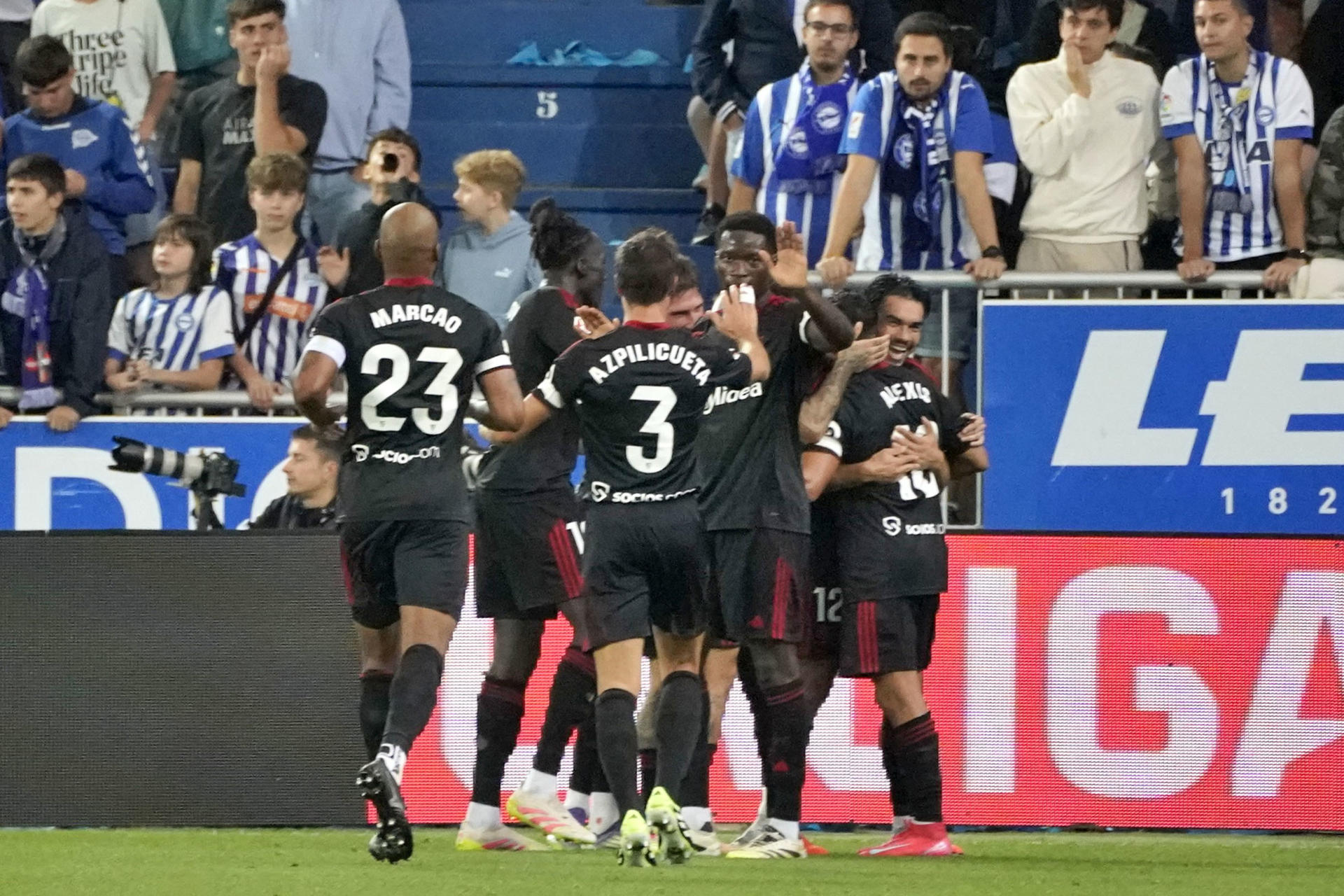 El delantero chileno del Sevilla FC Alexis Sánchez (d) celebra con sus compañeros tras anotar un gol durante el partido de la quinta jornada de LaLiga EA Sports disputado en el estadio de Mendizorroza, en Vitoria. EFE/L. Rico
