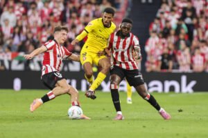 El centrocampista marroquí del Girona Azzedine Ounahi (c) disputa el balón ante los jugadores del Athletic, Mikel Jauregizar (i) e Iñaki Williams, durante el partido de la jornada 6 de LaLiga EA Sports disputado el martes en San Mamés. EFE/Luis Tejido