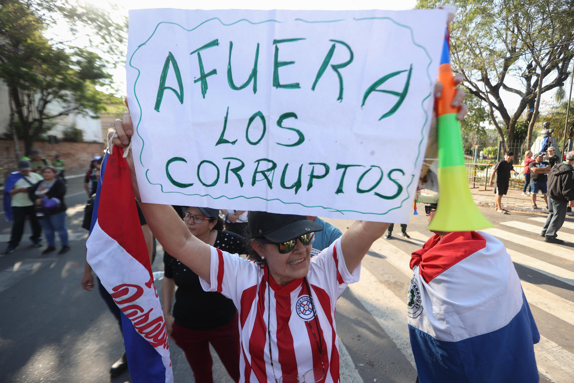 Una mujer sostiene un cartel durante una manifestación este domingo, en Asunción (Paraguay). EFE/ Juan Pablo Pino