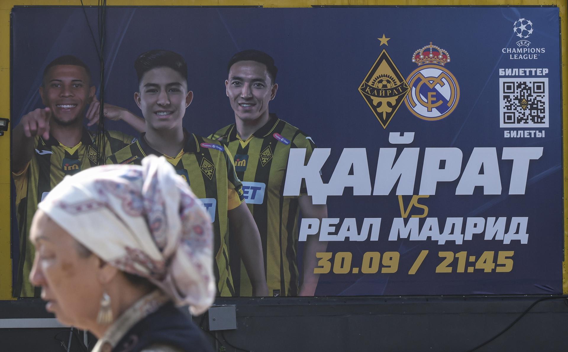 Una mujer pasa junto al cartel que anuncia el partido entre el Kairat Almaty y el Real Madrid, de la segunda jornada de la Liga de Campeones. EFE/EPA/MAXIM SHIPENKOV