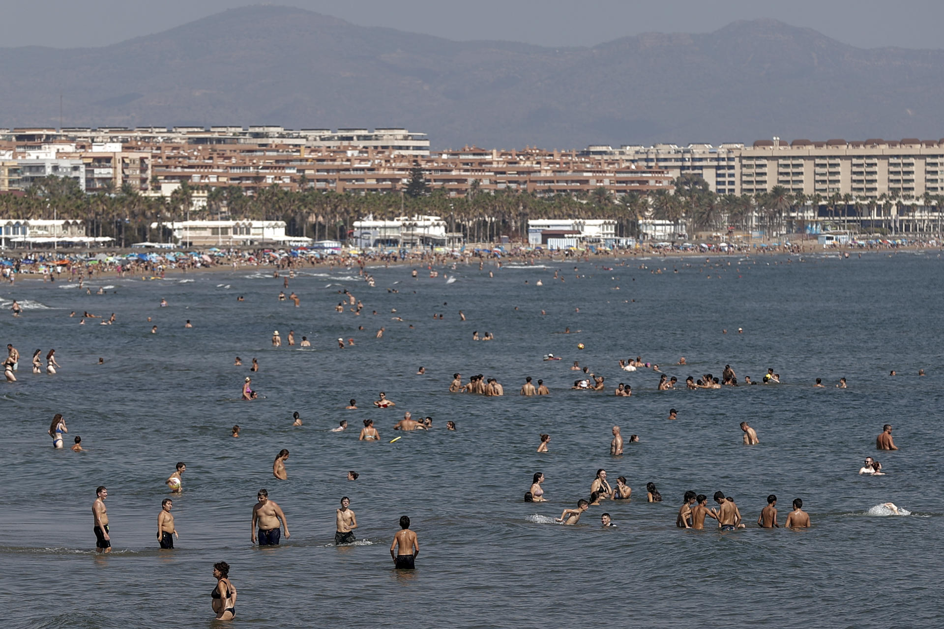 Un gran número de personas se refresca en aguas de la playa de la Malvarrosa durante este lunes. EFE/Manuel Bruque