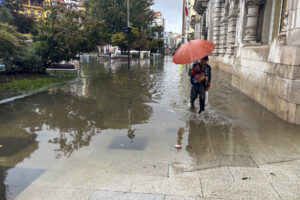 Una mujer intenta atravesar una calle inundada de Santander durante la tormenta registrada este lunes. EFE/ Kike Serrano Mirones