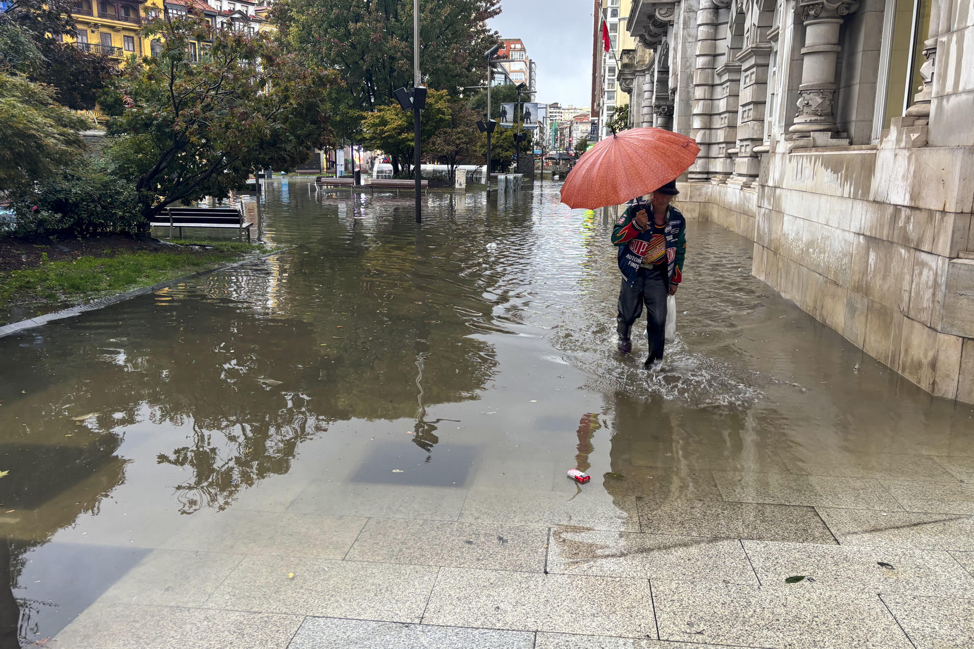 Una mujer intenta atravesar una calle inundada de Santander durante la tormenta registrada este lunes. EFE/ Kike Serrano Mirones