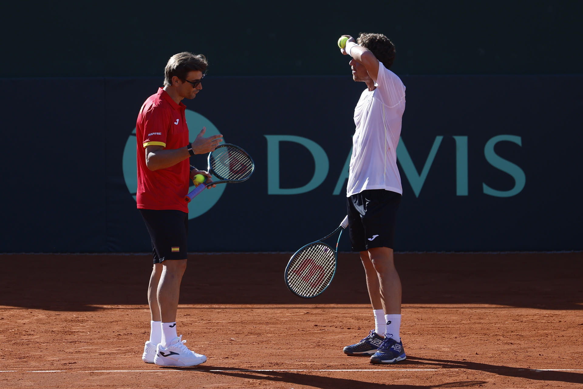 El tenista Roberto Carballés (d), y David Ferrer (i), capitán del equipo español de Copa Davis, este miércoles durante la jornada de entrenamiento en la pista central del Club de Tenis Puente Romano de Marbella, donde este fin de semana jugará la segunda ronda clasificatoria de la Copa Davis 2025 contra Dinamarca.-EFE/ Jorge Zapata