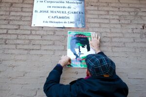 Imagen de archivo (04/12/2012).- Un hombre pega un cartel con la imagen del joven sindicalista Manuel José García Caparrós, debajo de la placa situada en el lugar donde murió por un disparo en la manifestación del 4 de diciembre de 1977 en Málaga y donde se ha realizado hoy una ofrenda floral tras lo que IU ha anunciado que será nombrado Hijo Predilecto de la comunidad el próximo 28 de febrero. EFE/Jorge Zapata