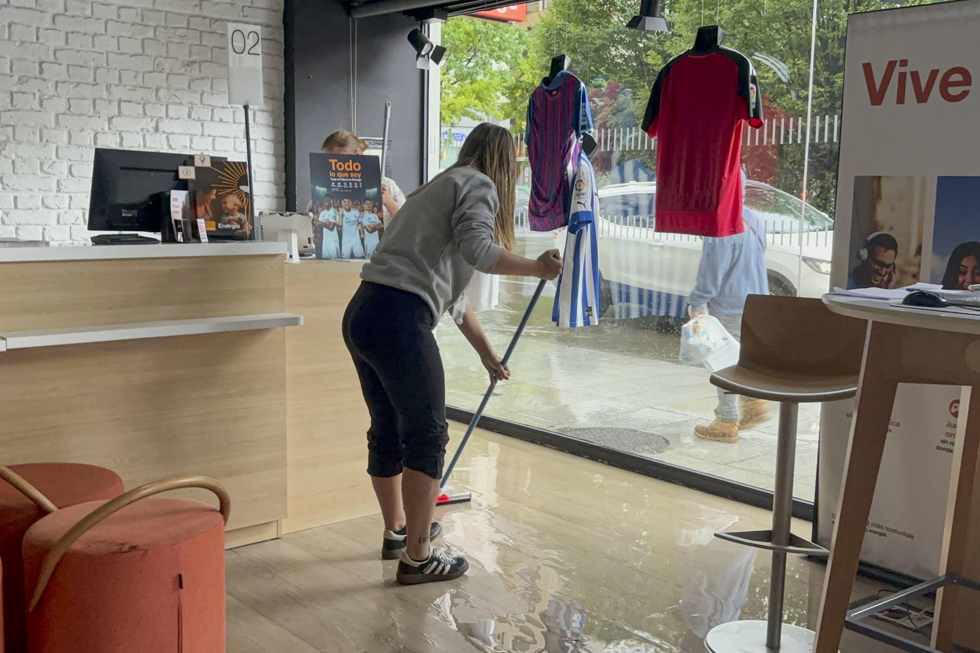 Una mujer limpia una tienda inundada por la tormenta registrada este lunes. EFE/ Kike Serrano Mirones
