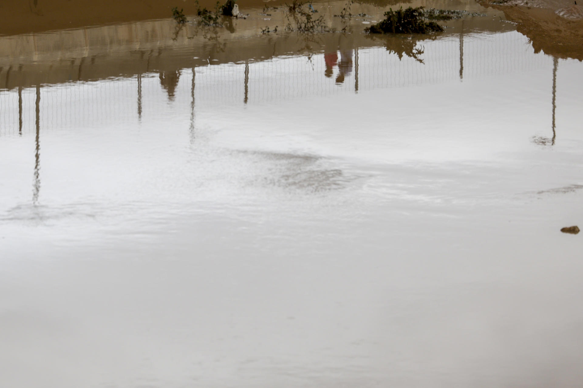 Reflejo de gente cruzando por el barranco del Poyo a su paso por Paiporta, Valencia,. EFE/ Kai Försterling
