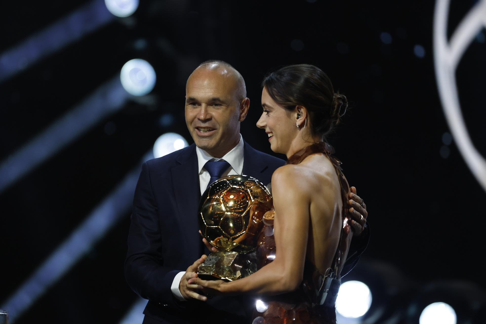 La futbolista del F.C. Barcelona Aitana Bonmatí (d) recibe de manos del exinternacional español Andrés Iniesta (i) el Balón de Oro femenino en la gala celebrada este lunes en París. EFE/ Mohammed Badra

