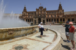 Imagen de turistas refrescándose en la fuente de la Plaza de España de Sevilla en agosto pasado. EFE/ Raúl Caro.