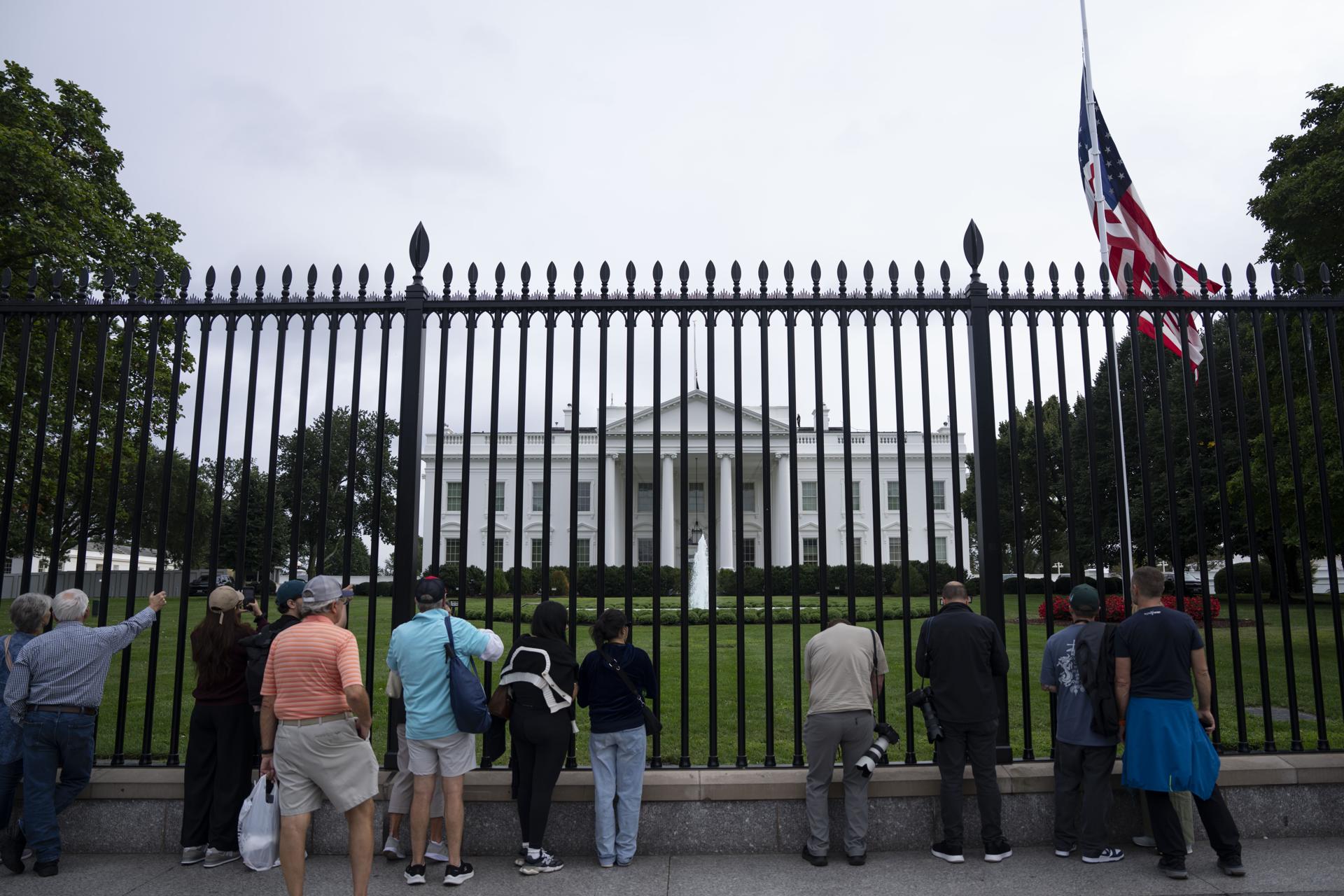 Visitantes observan la bandera estadounidense a media asta frente a la Casa Blanca, en Washington, tras el asesinato del activista conservador Charlie Kirk. EFE/Kayla Bartkowski