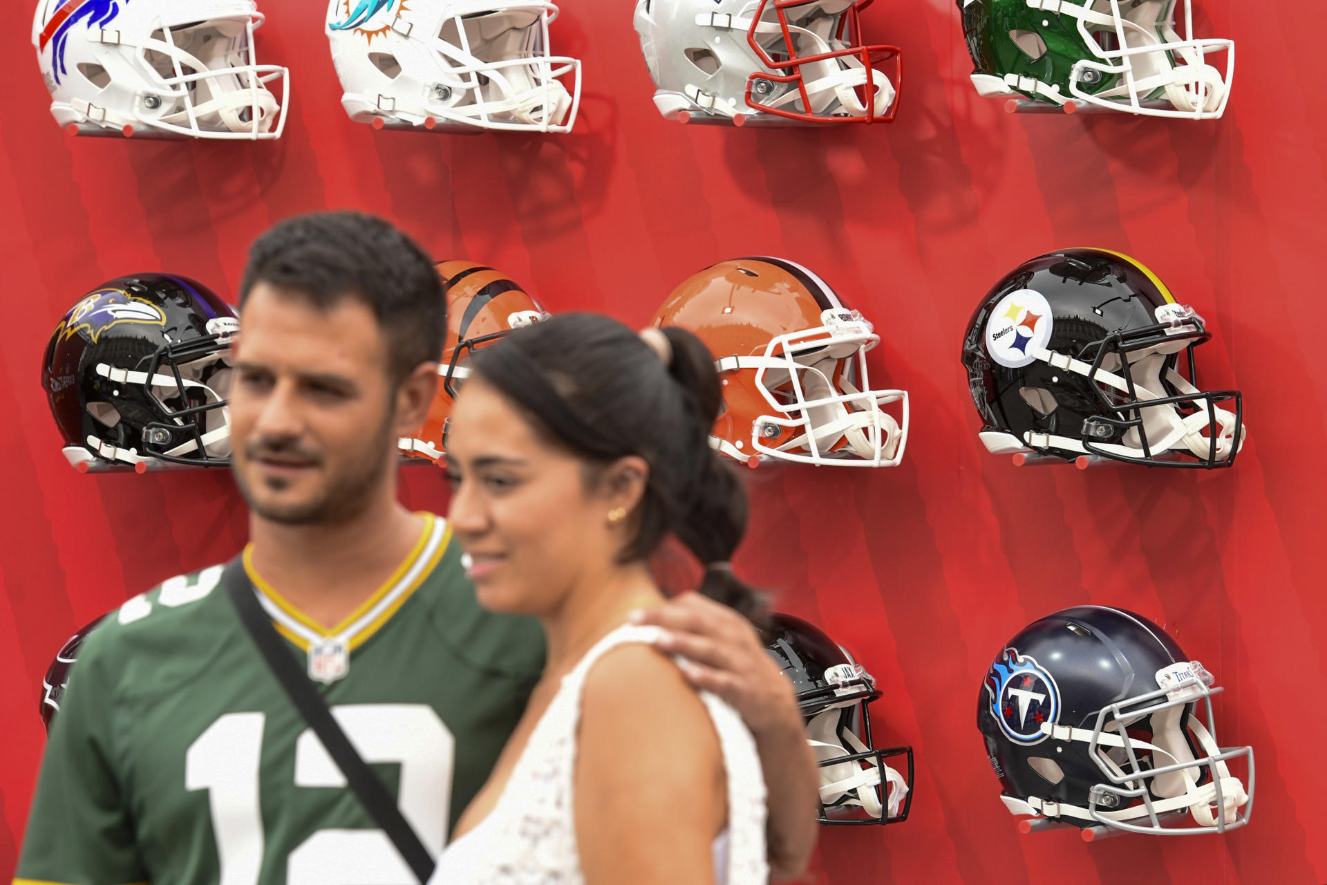 Asistentes a la ´NFL Experience Madrid Watch Party´ se fotografían junto a la exposición de cascos de los distintos equipos de la NFL antes del inicio de la retransmisión del encuentro en directo entre los Miami Dolphins e Indianapolis Colts, hoy Domingo en la Plaza de Oriente, en Madrid. EFE / Victor Lerena.