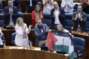 La portavoz del PSOE en la Asamblea de Madrid, Mar Espinar (d), sostiene la bandera de Palestina durante su intervención en el pleno celebrado, este jueves, en la Asamblea de Madrid. EFE/ Sergio Pérez