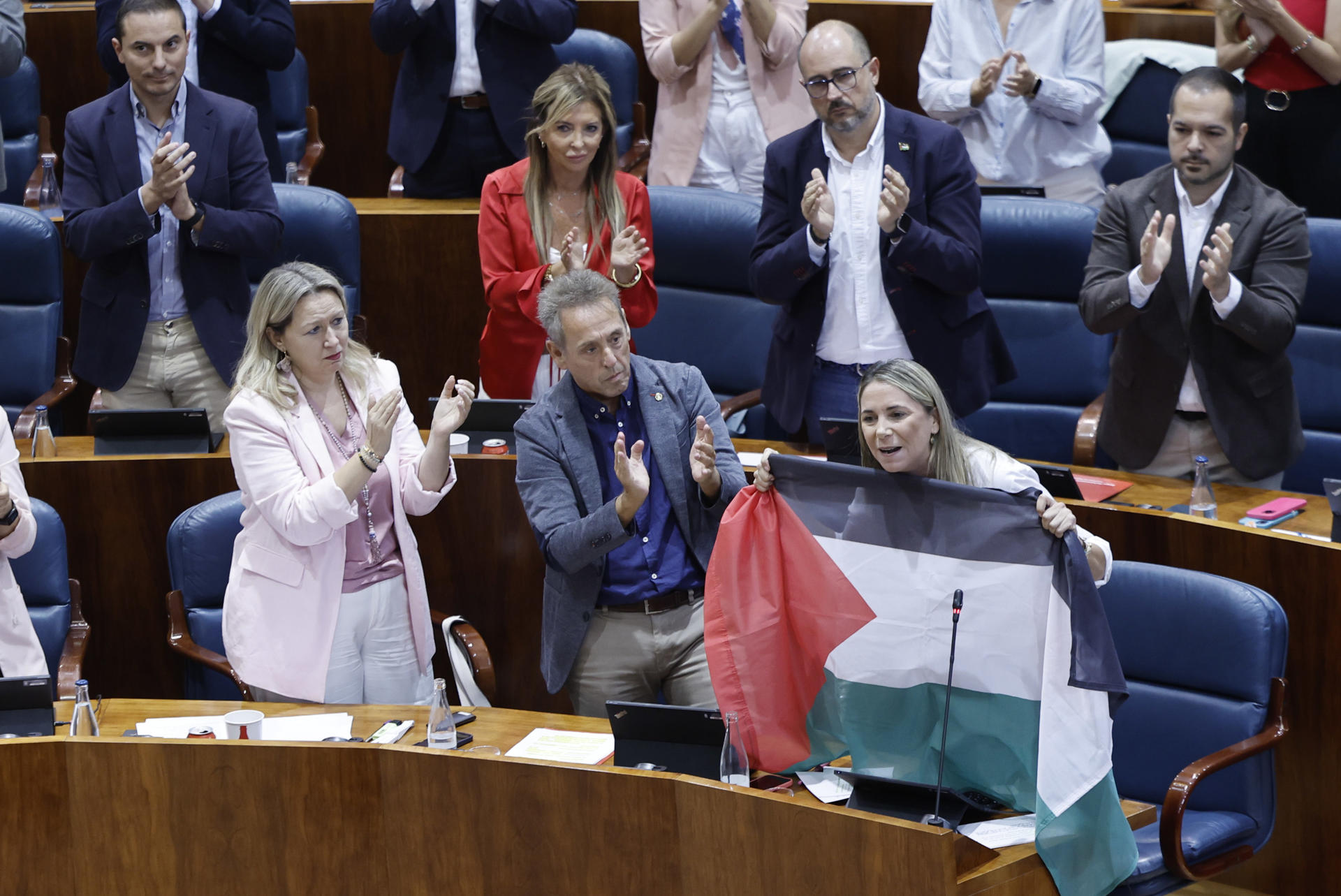 La portavoz del PSOE en la Asamblea de Madrid, Mar Espinar (d), sostiene la bandera de Palestina durante su intervención en el pleno celebrado, este jueves, en la Asamblea de Madrid. EFE/ Sergio Pérez