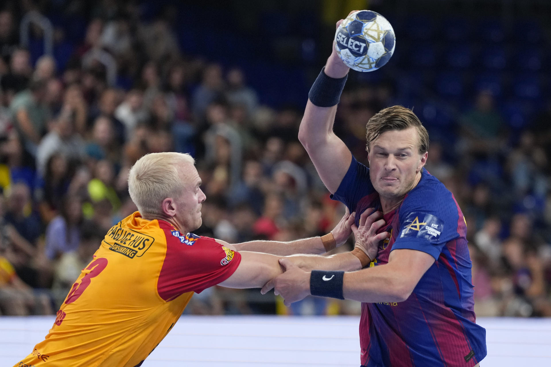 El extremo sueco del Barça Jonathan Carlsbogård (d) lucha con el noruego Henrik Jakobsen, del GOG Gudme, durante el partido de Liga de Campeones de balonmano que Barça y GOG Gudme disputan hoy jueves en el Palau Blaugrana. EFE/Alejandro García