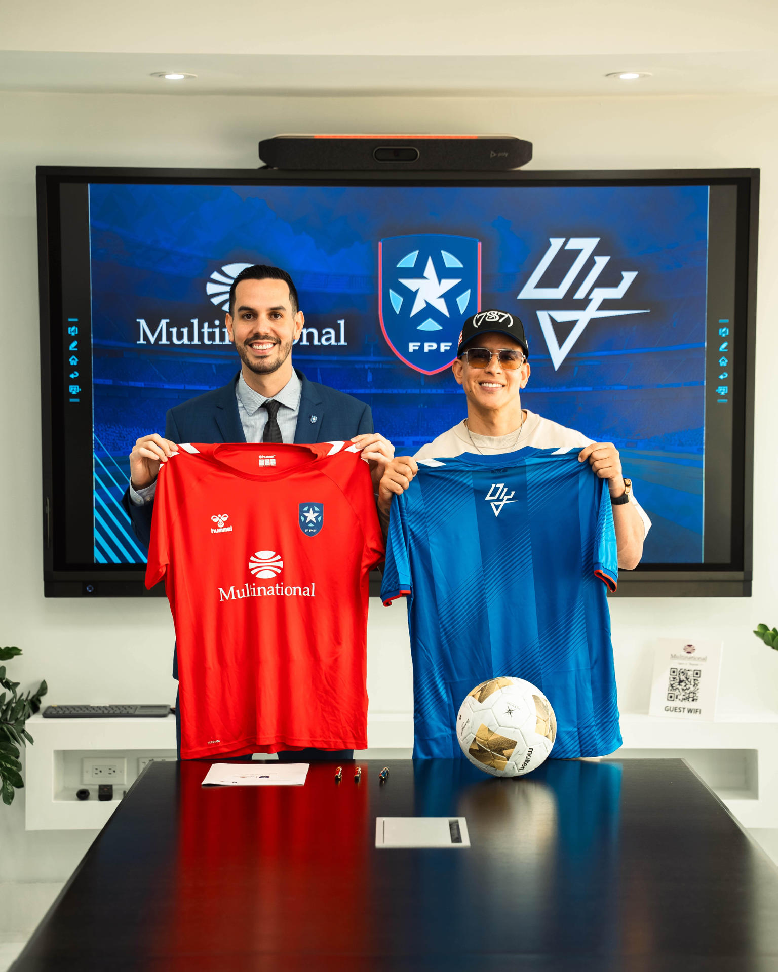 Fotografía cedida por la Federación Puertorriqueña de Fútbol (FPF), donde aparece su presidente, Iván Rivera (i), y el artista puertorriqueño Daddy Yankee (d), durante la firma de un acuerdo de cooperación interinstitucional con la empresa Multinational para continuar desarrollando el deporte en Puerto Rico. EFE/FPF
