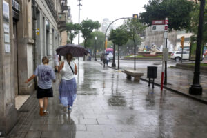 Imagen de dos personas protegiéndose de la lluvia en el centro de Tarragona, en julio pasado. EFE/Javier Díaz