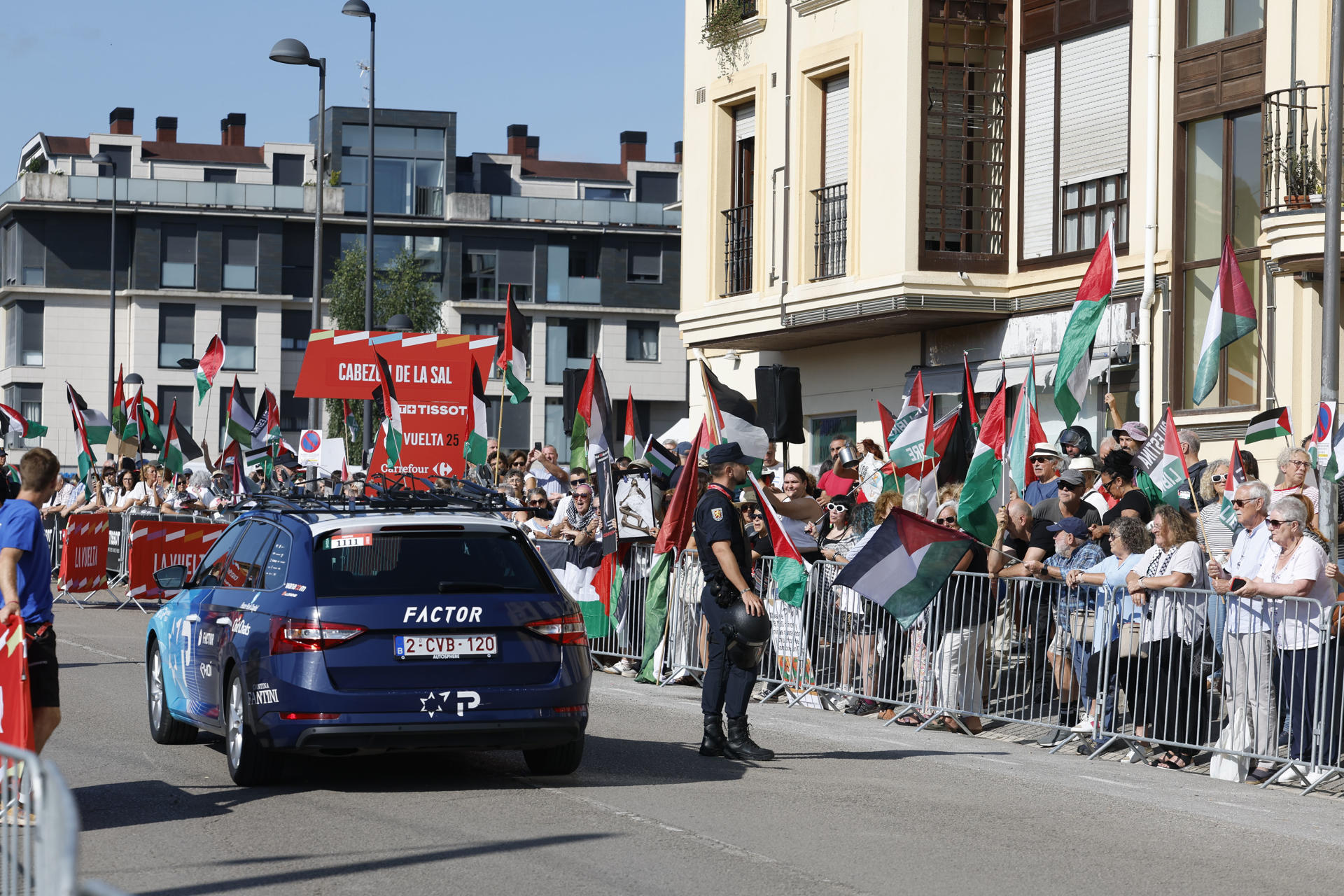 El coche del equipo Israel Tech pasa junto a manifestantes de apoyo a Palestina antes del comienzo de la etapa 13 de la Vuelta Ciclista a España 2025 disputada entre el Cabezón de la Sal, y L'Angliru, de 202,7km de recorrido, este viernes. EFE/Javier Lizón