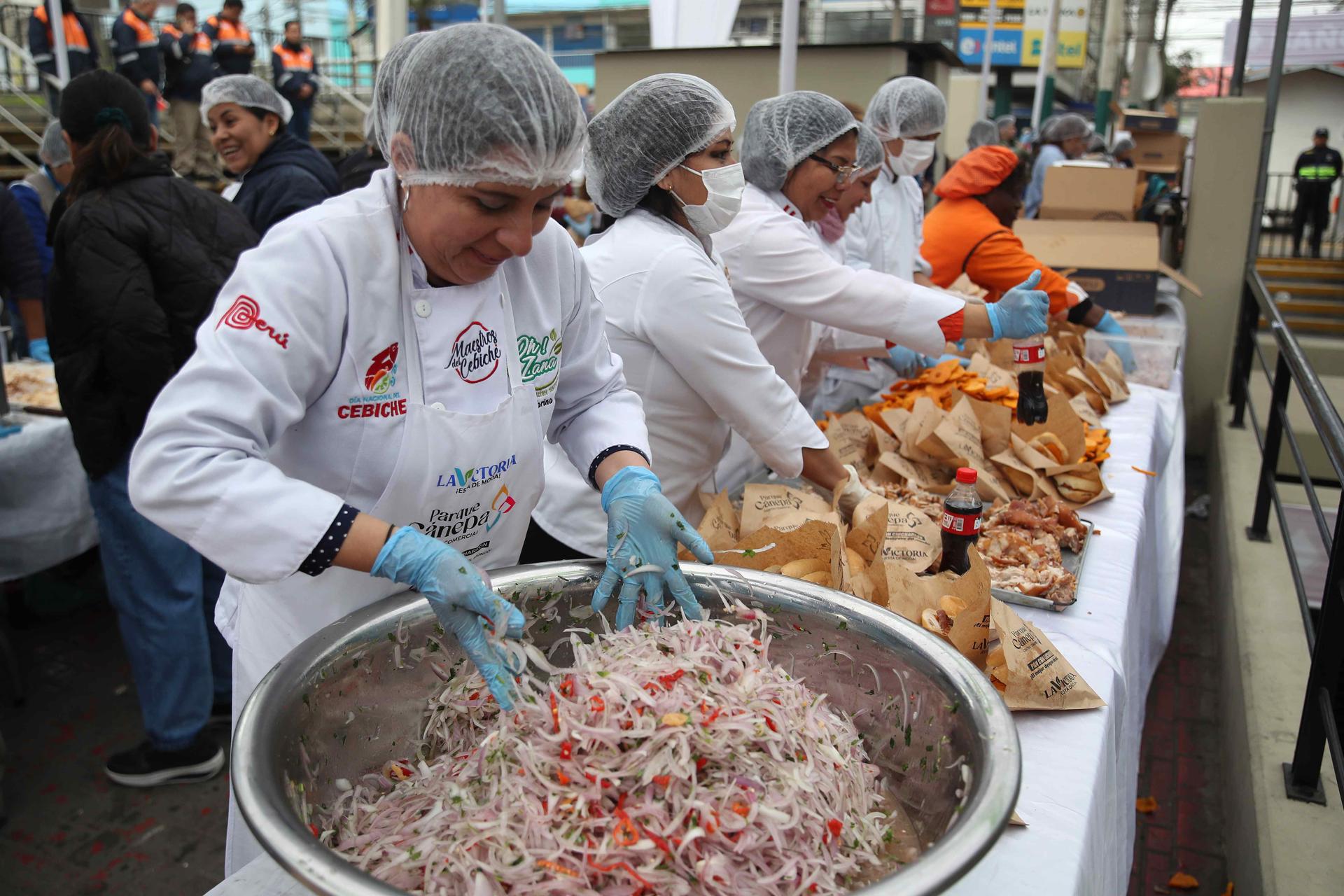 Personas preparan panes con chicharrón este viernes, en Lima (Perú). EFE/ Paolo Aguilar