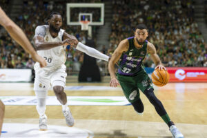 El alero dominicano de Unicaja, Chris Duarte (d), con el balón ante la defensa del pivot angoleño del Real Madrid, Bruno Fernando, durante el tercer partido del XIV Torneo Costa del Sol que han disputado hoy domingo Unicaja y Real Madrid en el Palacio de los Deportes José María Martín Carpena de Málaga. EFE/Carlos Díaz.