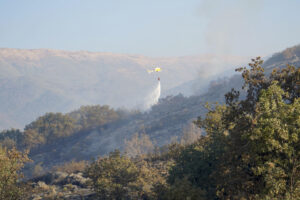 Un helicóptero trabaja en las labores de extinción del incendio forestal declarado este domingo en Cuacos de Yuste (Cáceres), que ha arrasado 438 hectáreas de matorral y arbolado. EFE/  EDUARDO PALOMO