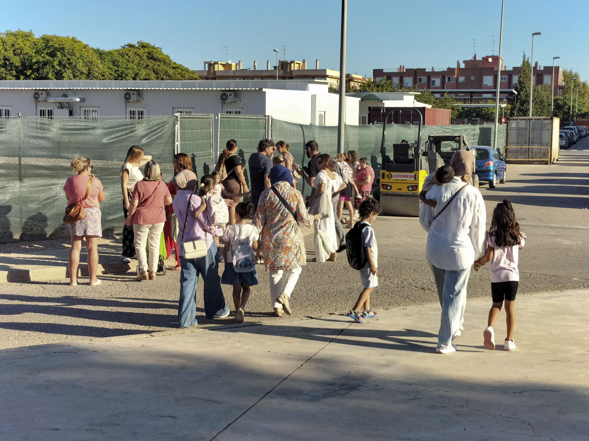 Un grupo de niños y niñas espera junto a sus padres a las puertas del CEIP Orba de Alfafar. EFE/Eusebio Calatayud
