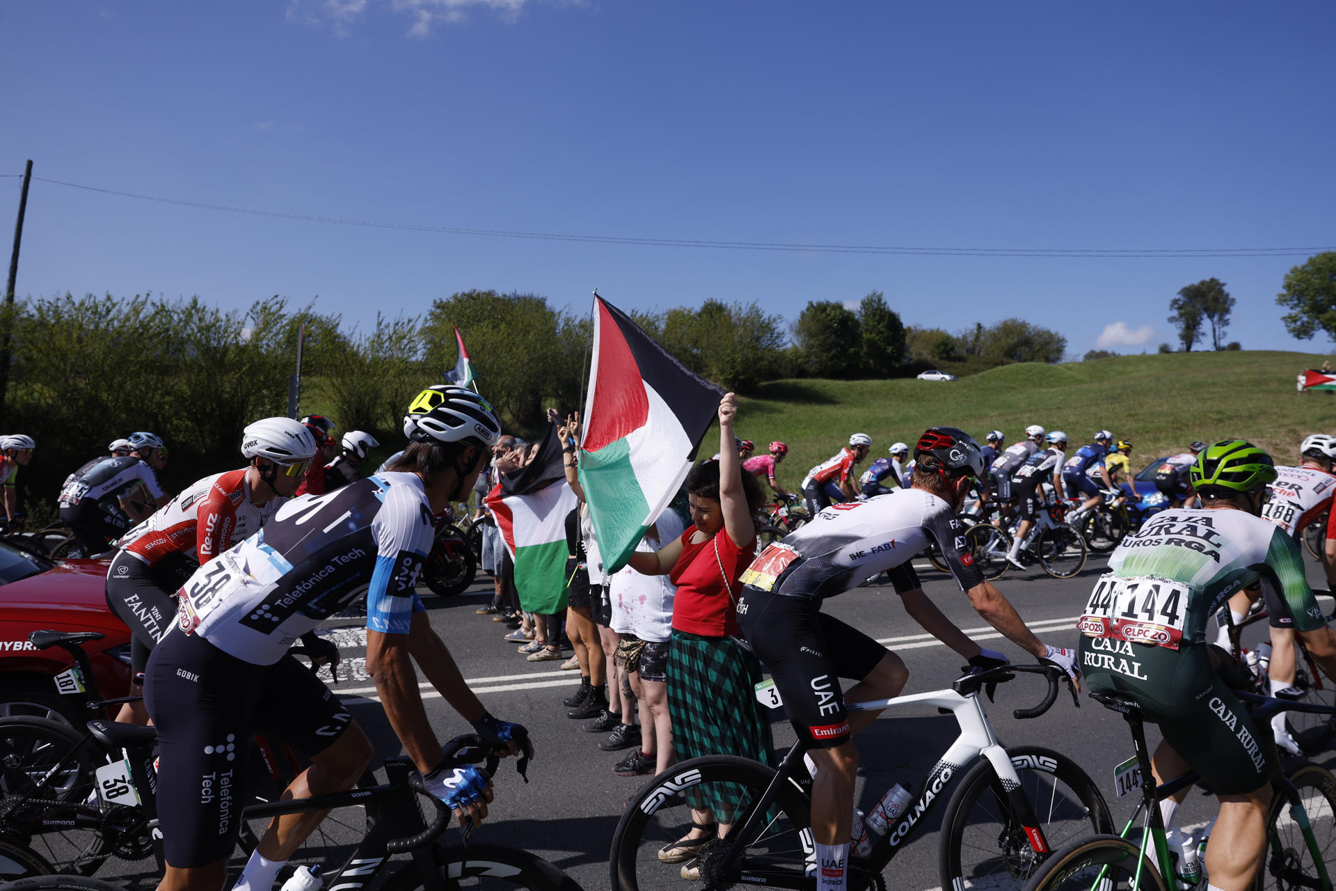 Varias personas protestas en apoyo al pueblo palestino entre los ciclistas durante la etapa 13 de la Vuelta Ciclista a España 2025 disputada entre el Cabezón de la Sal, y L'Angliru, de 202,7km de recorrido, este viernes. EFE/Javier Lizón