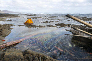 El Ministerio de Transportes ha decidido mantener al menos 24 horas más la emergencia por contaminación marítima decretada en Lanzarote tras encallar e incendiarse un pesquero marroquí en la costa de Órzola, pero solo por precaución, ya que el impacto del gasóleo derramado "es mínimo". En la imagen, tomada este jueves, restos del pesquero en la zona donde encalló, conocida como Charco de la Condesa, junto a la localidad de Órzola, en el norte de Lanzarote. En el agua, se aprecian algunas irisaciones generadas por la presencia de gasóleo. EFE/Adriel Perdomo