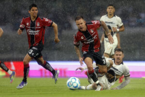Aaron Ramsey (d), de Pumas, disputa el balón con Carlos Orrantia (i) y Gustavo Ferrareis, de Atlas, durante un partido del Torneo Apertura 2025 de la Liga MX. EFE/ Sáshenka Gutiérrez