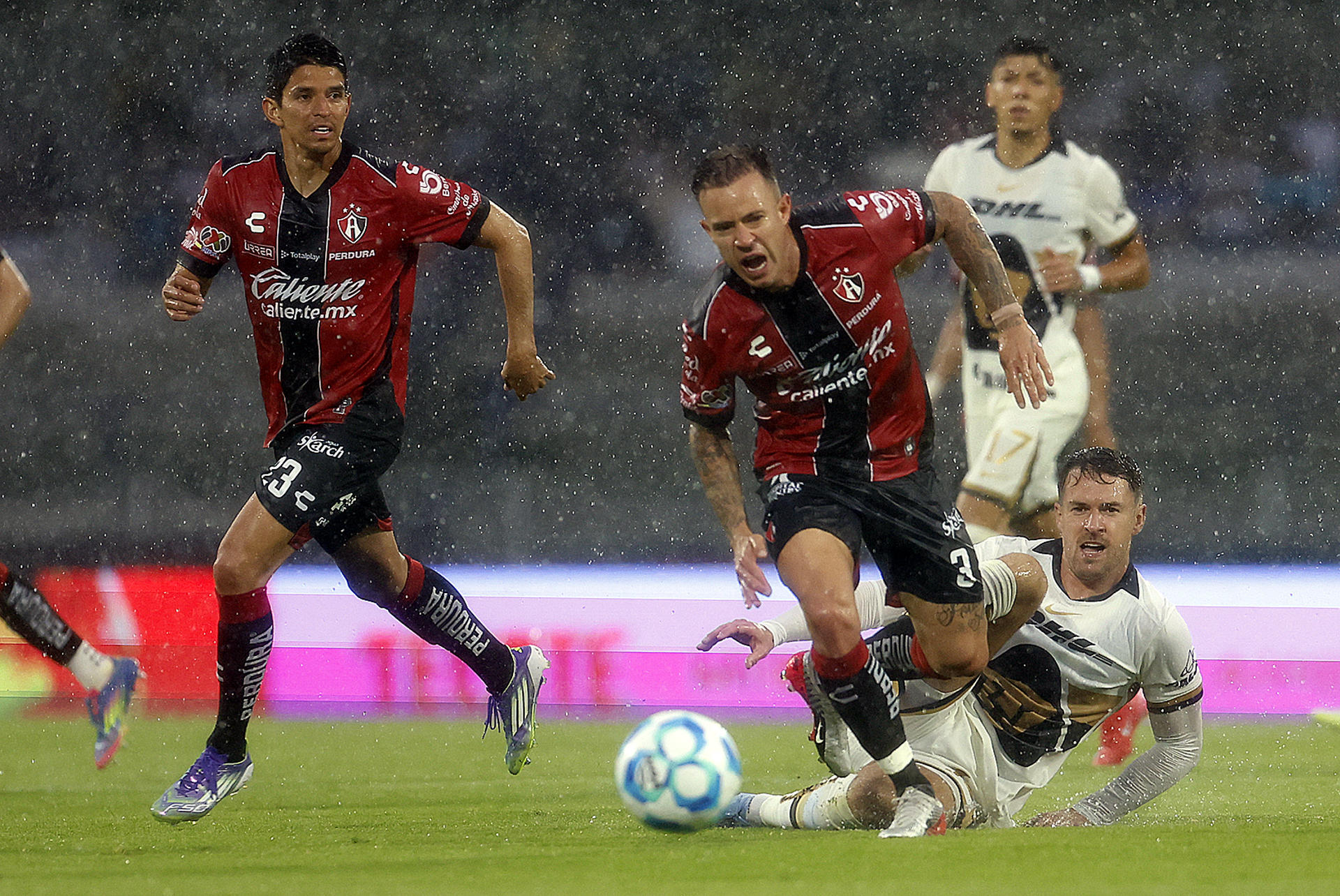 Aaron Ramsey (d), de Pumas, disputa el balón con Carlos Orrantia (i) y Gustavo Ferrareis, de Atlas, durante un partido del Torneo Apertura 2025 de la Liga MX. EFE/ Sáshenka Gutiérrez