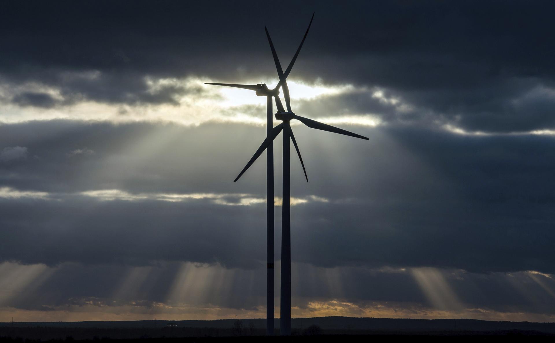Los rayos del sol se cuelan entre las nubes que cubren los molinos eólicos de la localidad de Sieversdorf, Alemania, en una imagen de archivo. EFE/Patricl Pleul