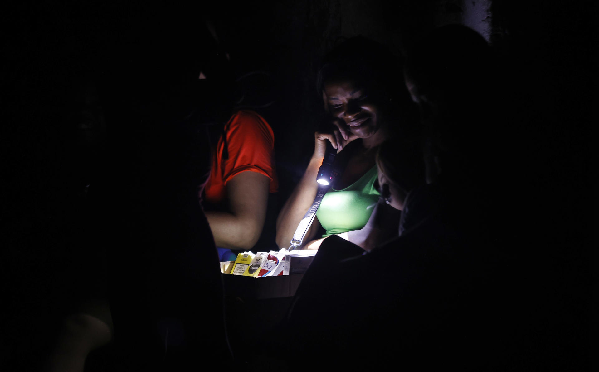 Una mujer ilumina con una linterna cigarros para venderlos durante un apagón este 10 de septiembre de 2025, en La Habana (Cuba). EFE/Ernesto Mastrascusa