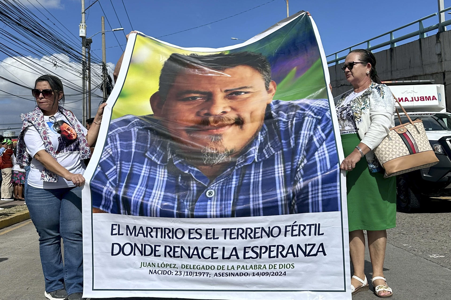 Dos mujeres sostienen un retrato del ambientalista hondureño Juan López durante una peregrinación este sábado, en Tegucigalpa (Honduras). EFE/Germán Reyes