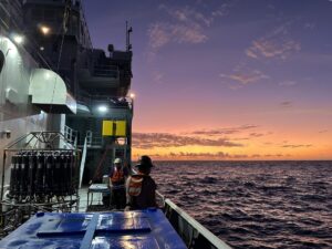 Puesta de sol a bordo del Thomas G. Thompson, un buque de investigación operado por la Universidad de Washington y equipado para viajes oceánicos. El instrumento que se ve a la izquierda es un muestreador de agua que puede recoger muestras a diferentes profundidades. Crédito: Kathy Newer/Universidad de Washington