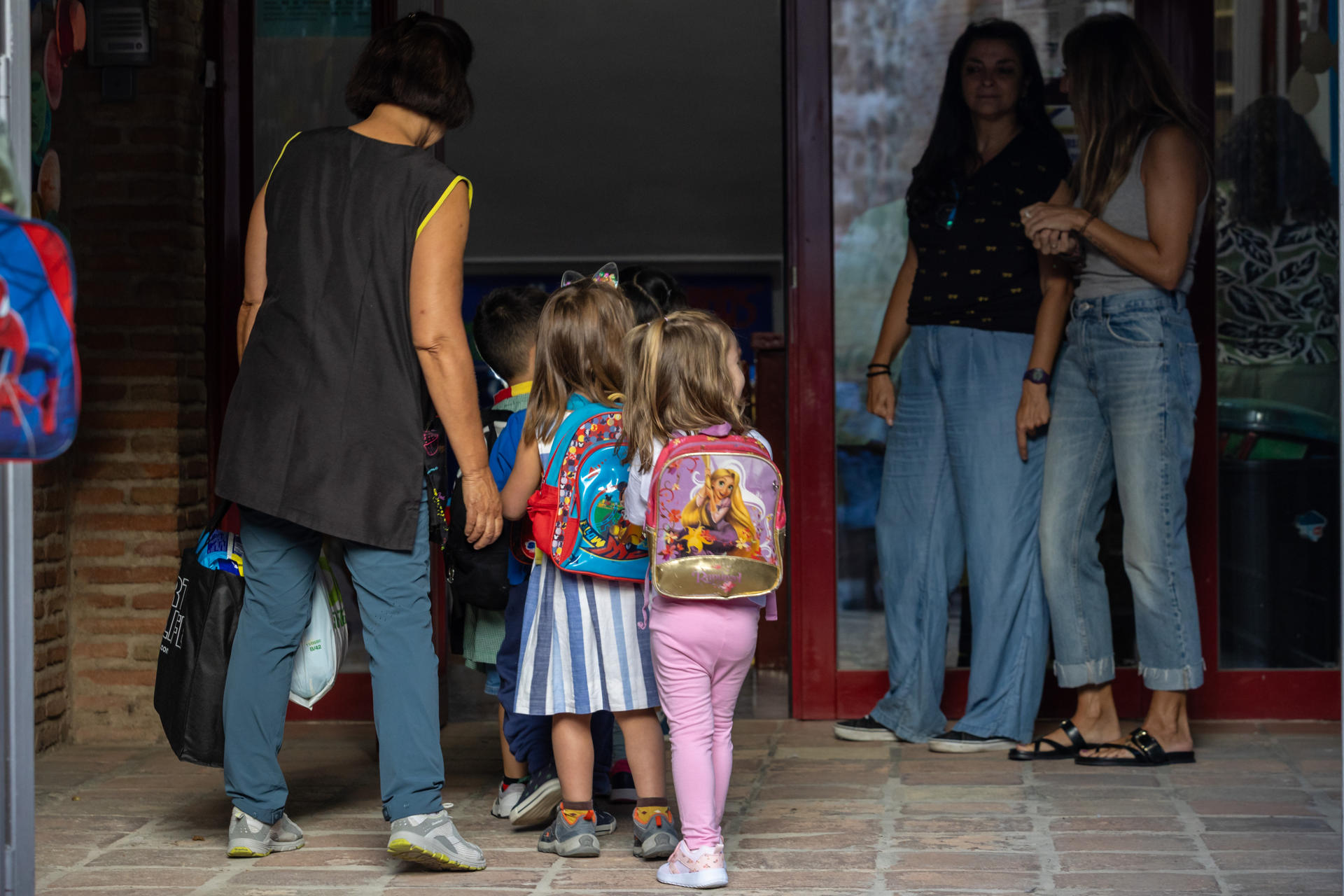 Varios padres con sus hijos a su llegada al Colegio San Lucas y María de Toledo, este lunes en el que da inicio el curso escolar. EFE/ Ángeles Visdómine
