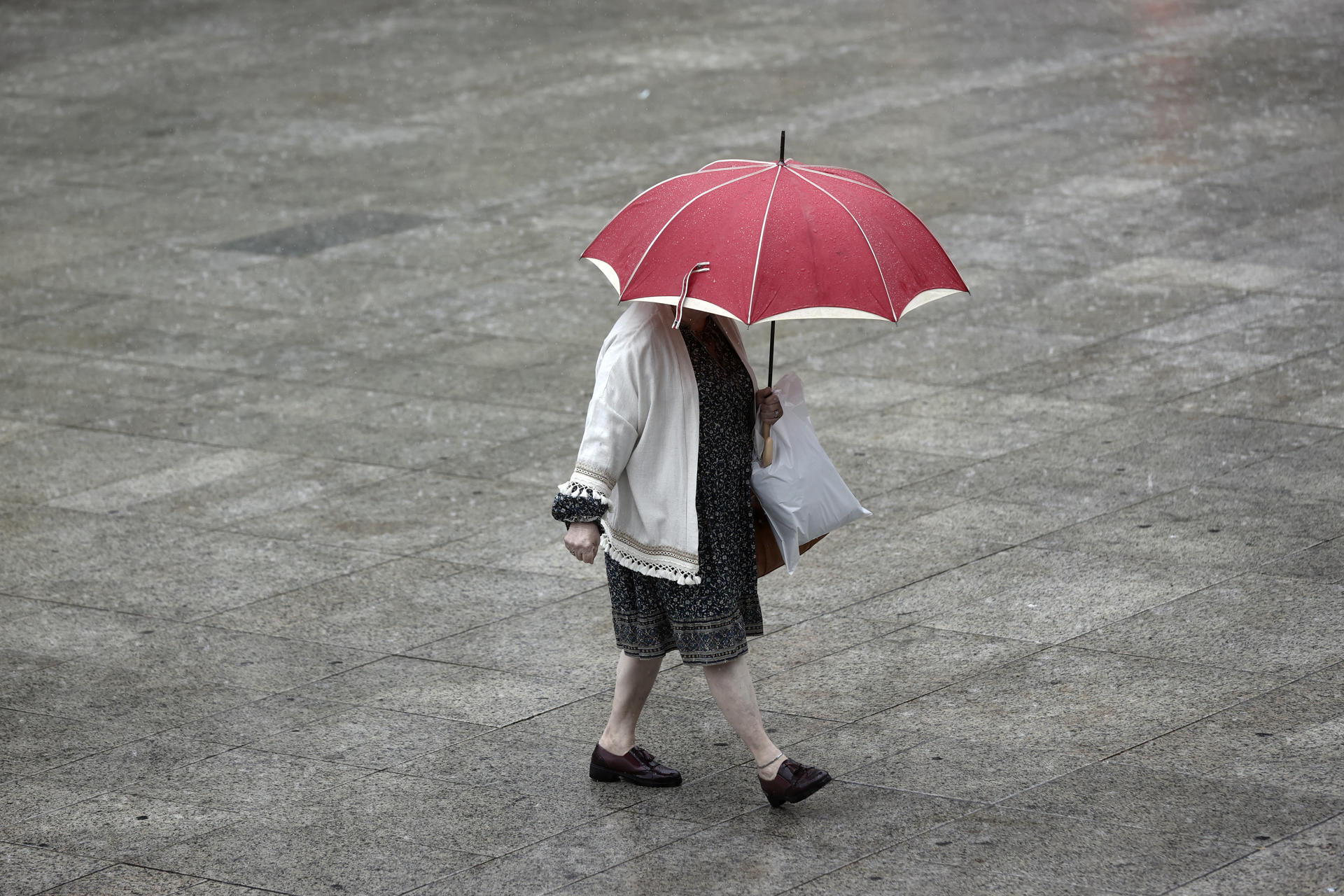 Una ujer se protege de la lluvia en una foto de archivo.. EFE/ Jesus Diges