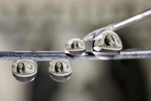 Fotografía que muestra billetes de un dolar reflejados en gotas de agua este lunes, en San José (Costa Rica). EFE/ Jeffrey Arguedas