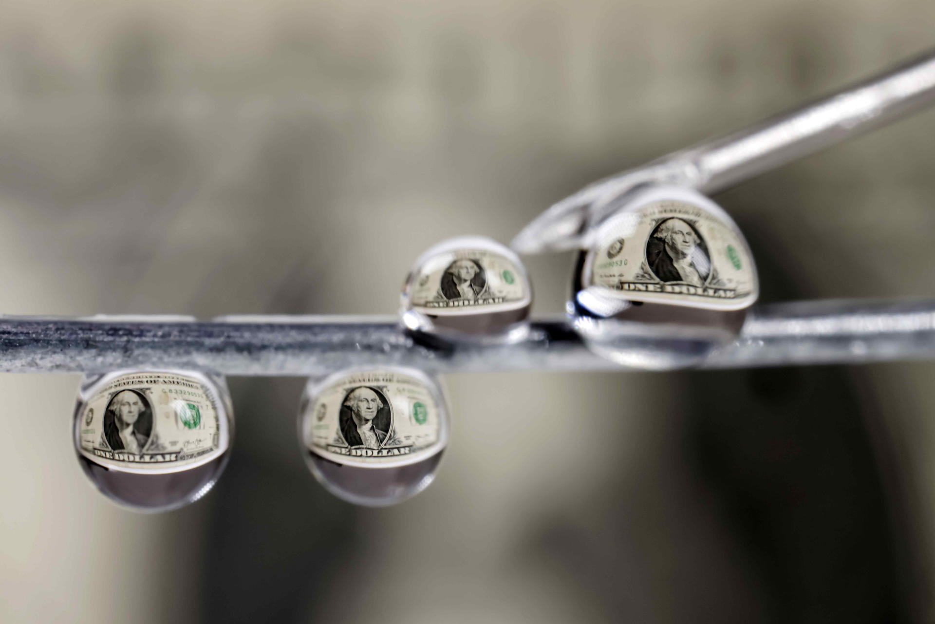 Fotografía que muestra billetes de un dolar reflejados en gotas de agua este lunes, en San José (Costa Rica). EFE/ Jeffrey Arguedas