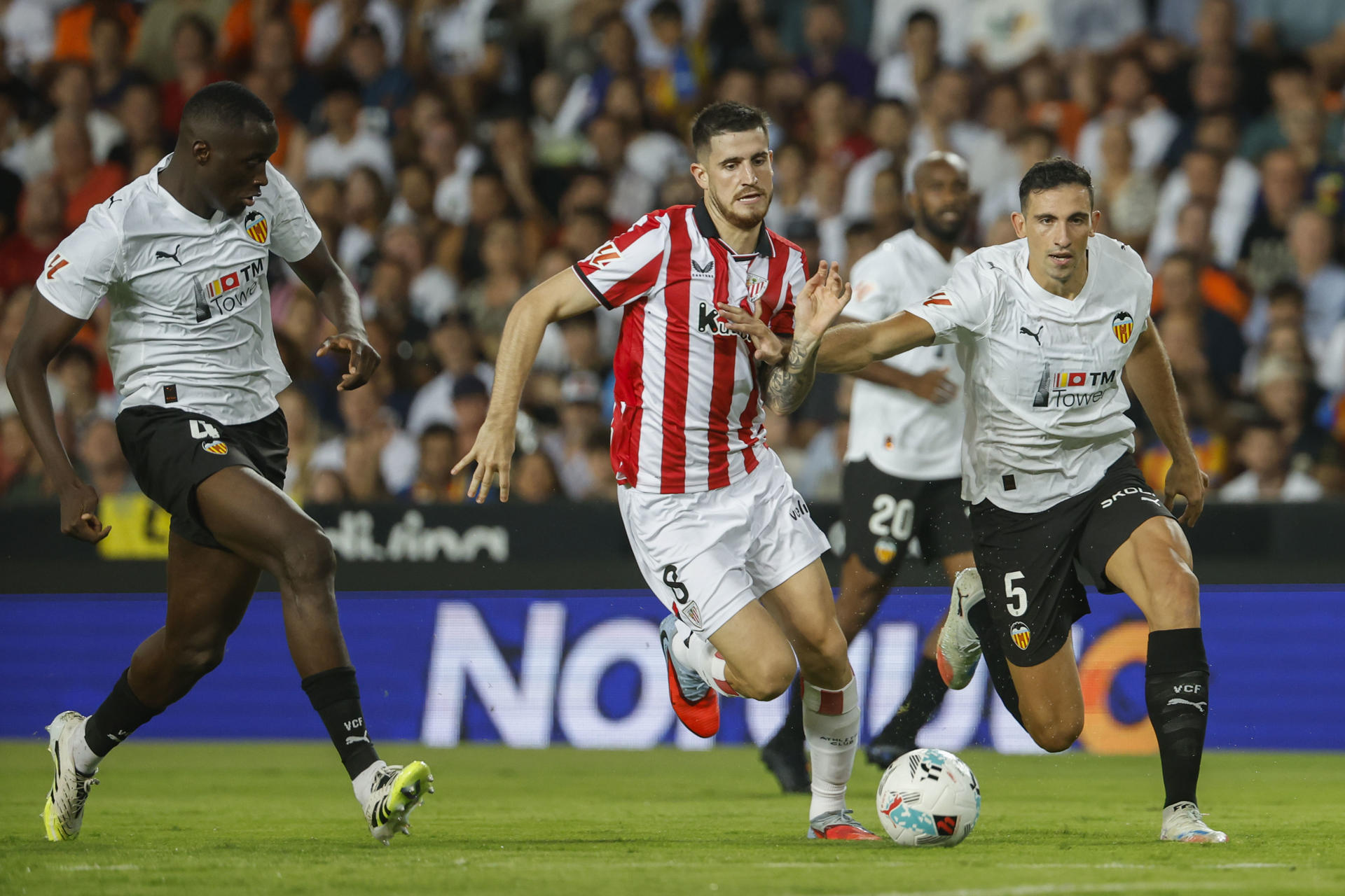 El defensa del Valencia César Tárrega (d) lucha con Oihan Sancet (c), del Athletic, durante el partido de la quinta jornada de LaLiga que Valencia CF y Athletic de Bilbao disputan este sábado en el estadio de Mestalla. EFE/Ana Escobar