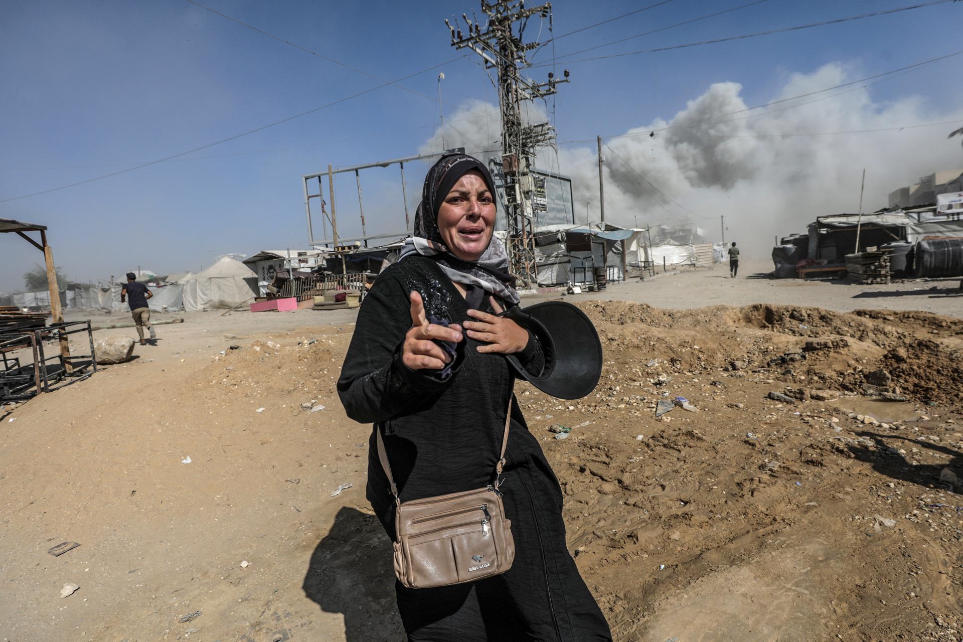 GAZA CITY (---), 08/09/2025.- A Palestinian woman runs for cover as smoke rises from the al-Roya residential building following an Israeli airstrike in the west of Gaza City, Gaza Strip, 08 September 2025. Israel confirmed the strike, claiming the building was housing 'intelligence gathering means'. EFE/EPA/MOHAMMED SABER
