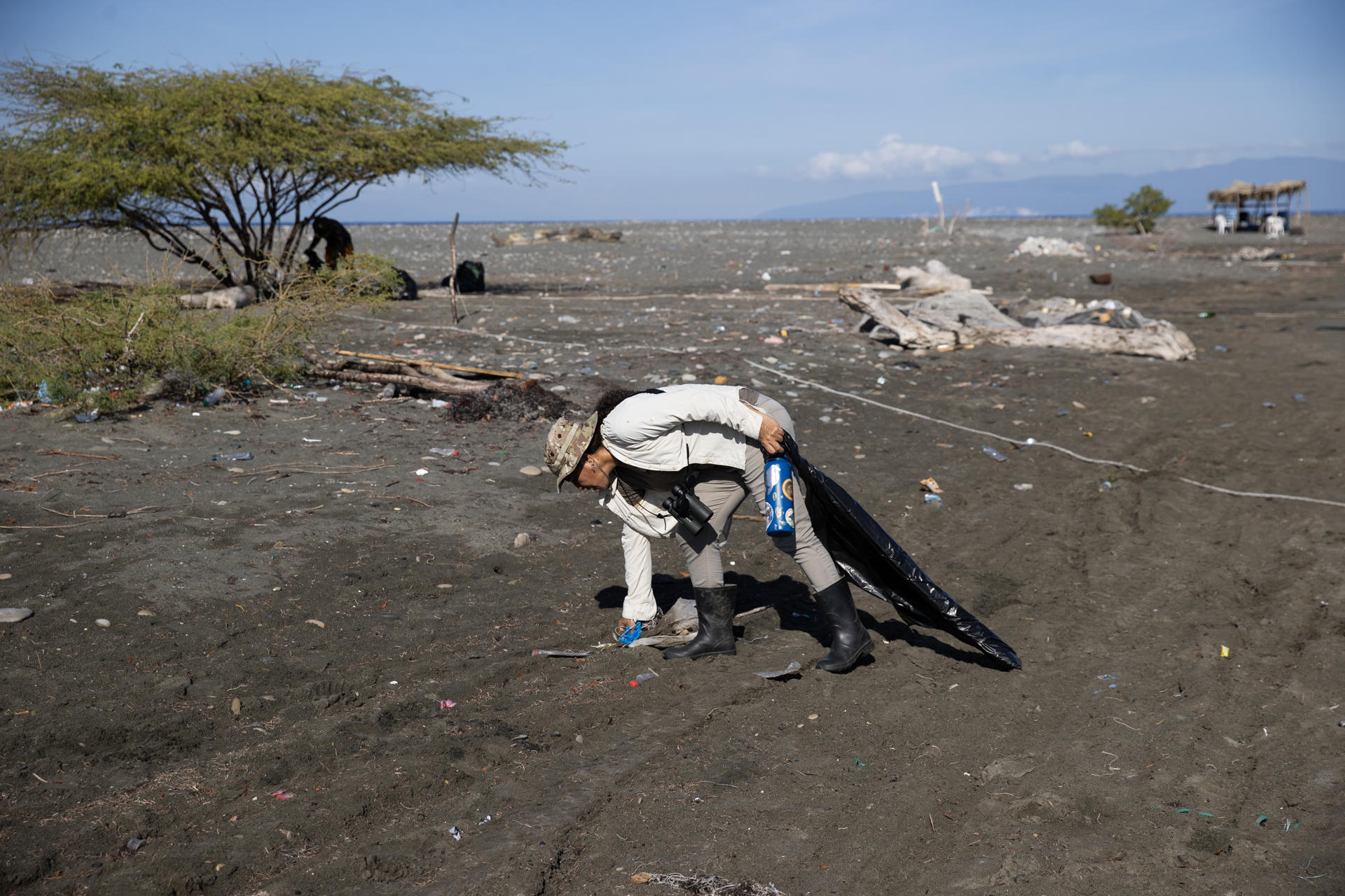 La directora de la organización Grupo Acción Ecológica (GAE), María Paulino, recoge desechos en una playa este jueves, en Las Salinas de Baní (República Dominicana). EFE/Orlando Barría