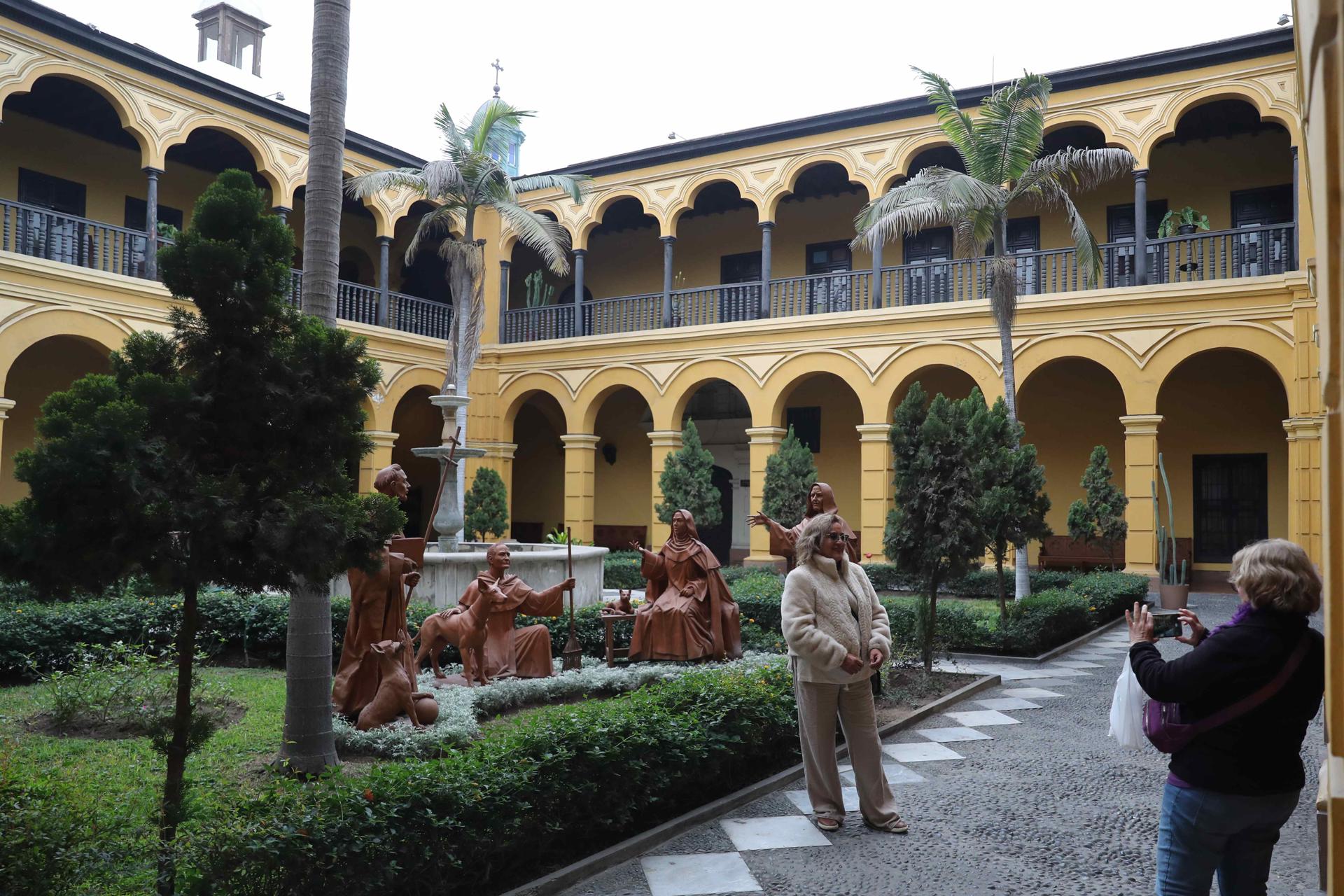 Personas se toman fotografías en un jardín del convento de Santo Domingo este lunes, en Lima (Perú). EFE/ Paolo Aguilar