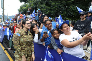 La ministra de Educación, Karla Trigueros (i), posa junto a asistentes en un desfile este lunes, en San Salvador (El Salvador). EFE/ Javier Aparicio